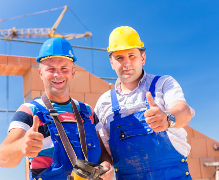 Construction site workers building walls on house