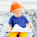 Portrait of little builder in hardhats reading construction drawing